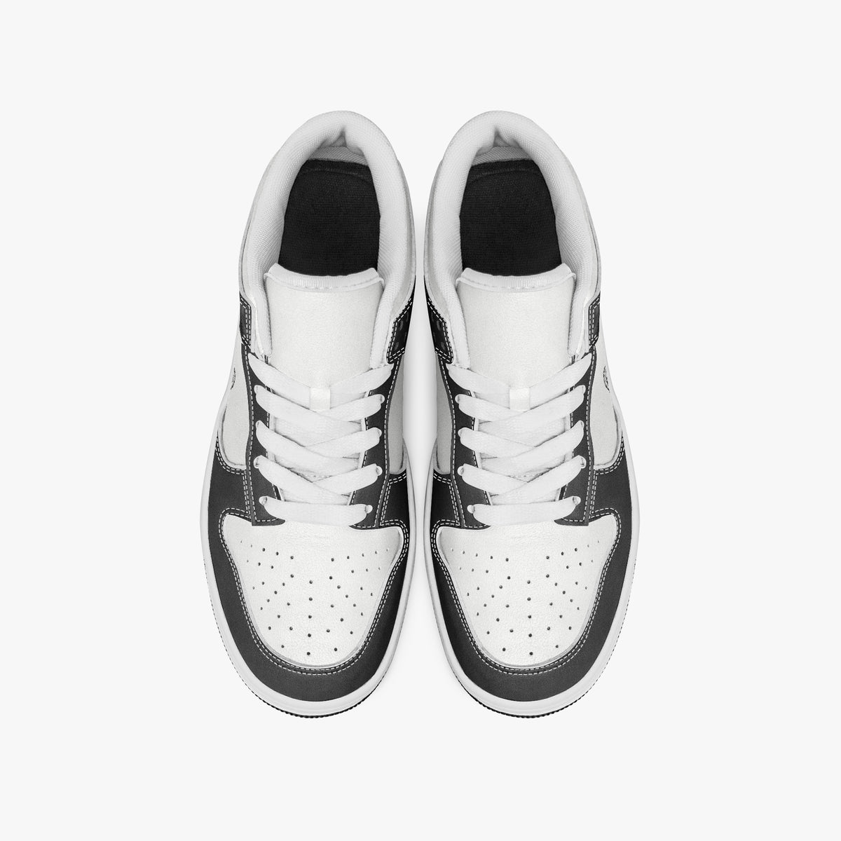 Overhead view of black and white sneakers showing clean white laces, white padded collar lining, and perforated white leather toe boxes.