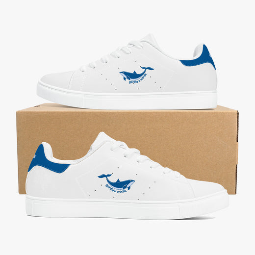 A pair of white low-top sneakers with blue heel accents and a blue whale logo on the side, displayed on a brown cardboard shoebox against a light gray background.