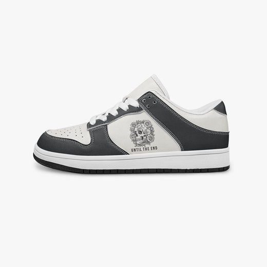 Side profile view of the left sneaker in black and white leather, highlighting the "UNTIL THE END" skull graphic, white laces, white interior lining, and flat rubber sole facing right.