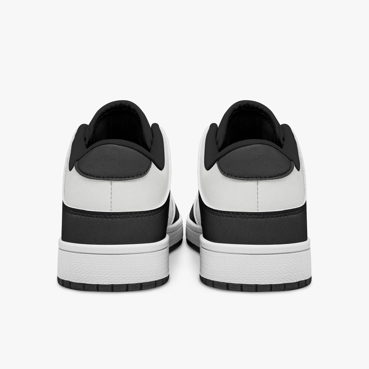 Rear view of black and white sneakers showing dark charcoal heel overlays, white leather collars, and black interior collar lining above white midsoles.
