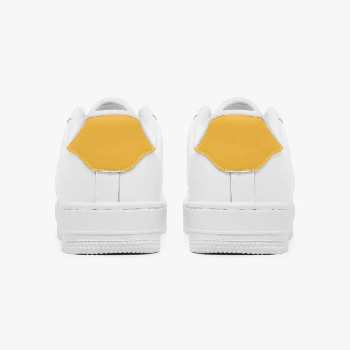 Rear view of white sneakers displaying mustard yellow heel tabs above thick white rubber outsoles.