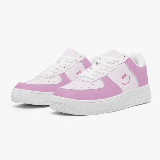 A pair of low-top sneakers in pastel pink and white, styled like classic Air Force 1 sneakers with a small pink graphic on the side, set against a clean white background.