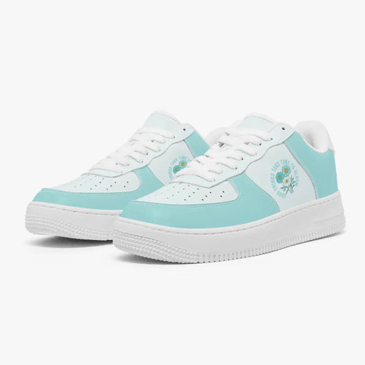 Angled three-quarter view of mint green and white sneakers featuring a floral graphic with the text "Good Things Take Time To Bloom" on the side panel.