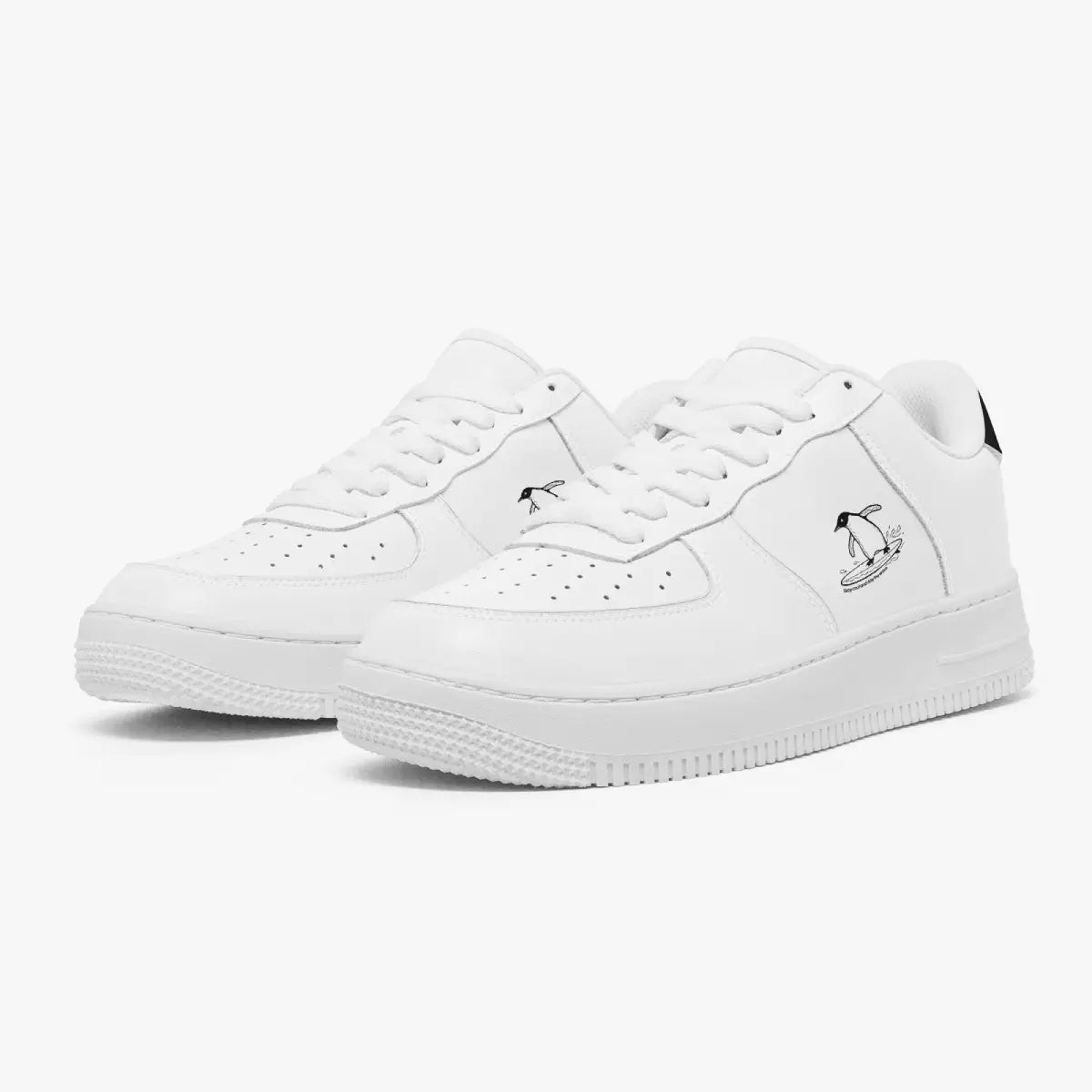 Angled three-quarter view of white leather sneakers featuring a minimalist black line-art penguin surfing graphic printed on the outer side panel.