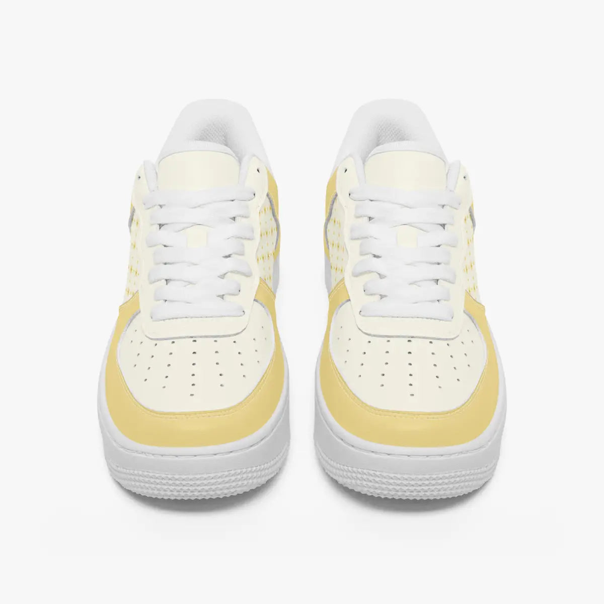 Front view of a pair of pastel yellow and cream low-top leather sneakers with white laces and perforated toe caps on a clean white background.