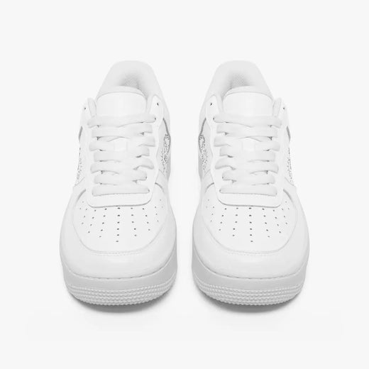 Front view of a pair of minimalist all-white low-top leather sneakers with white laces and perforated toe caps on an isolated white background.