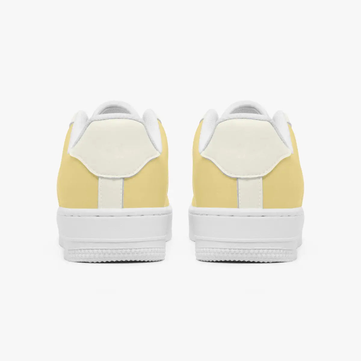 Rear view of a pair of pastel yellow and cream sneakers showing the padded heel counters and flat white rubber soles.