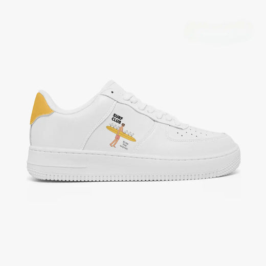Outer side view of the right sneaker in white leather, highlighting the surfer carrying a surfboard graphic and mustard yellow heel accent facing right.