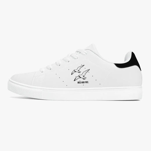 Side profile view of the left sneaker in white leather, showcasing the "WILD AND FREE" soaring birds illustration, black heel tab detail, white laces, and flat white rubber cupsole facing right.