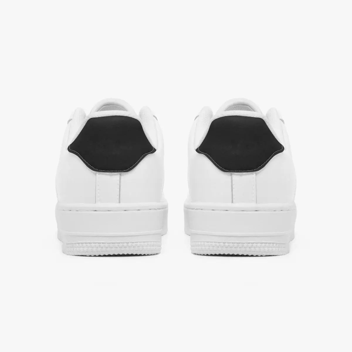 Rear view of white sneakers displaying contrasting black heel tabs, white leather collars, and textured white rubber platform midsoles.