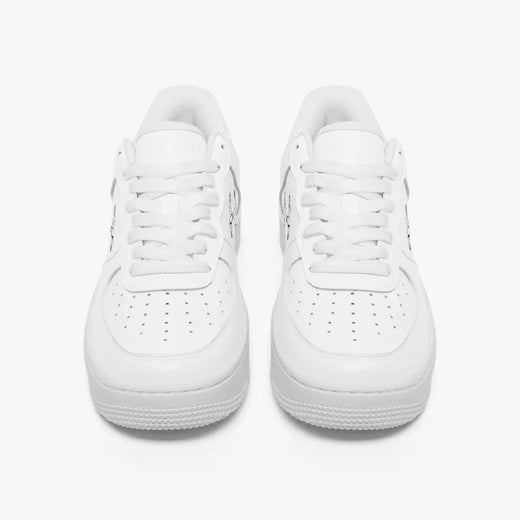 Front-facing top angle of monochromatic white leather low-top sneakers, displaying clean white laces, white eyestays, and perforated toe boxes.