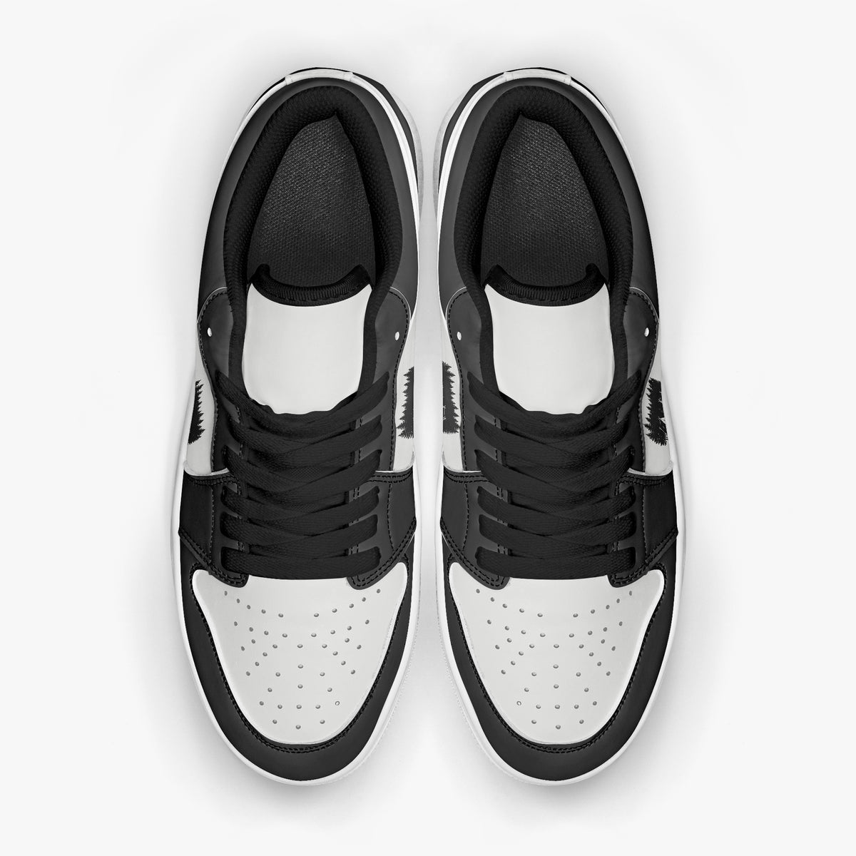 Overhead view of black and white sneakers displaying black laces, black padded collar lining, and perforated white leather toe boxes.