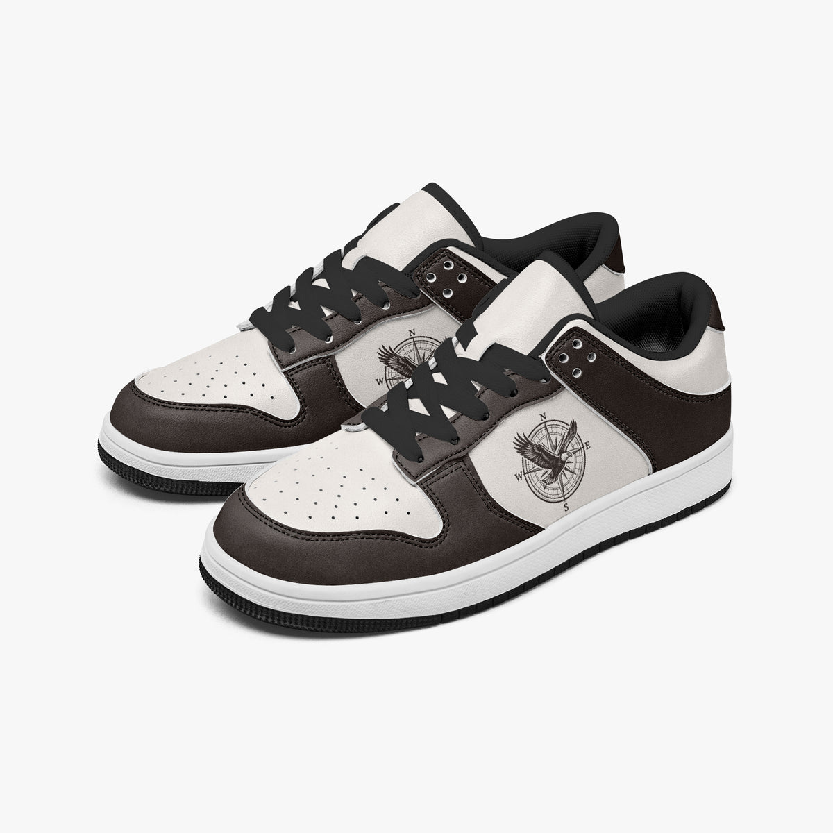 Angled three-quarter view of low-top sneakers in espresso dark brown and off-white leather, featuring an eagle and compass rose graphic, black laces, and a black inner lining.