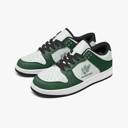 Angled three-quarter view of low-top sneakers in forest green and white leather, featuring a botanical leaves graphic with "PEACE OF MIND", black laces, and a black inner lining.