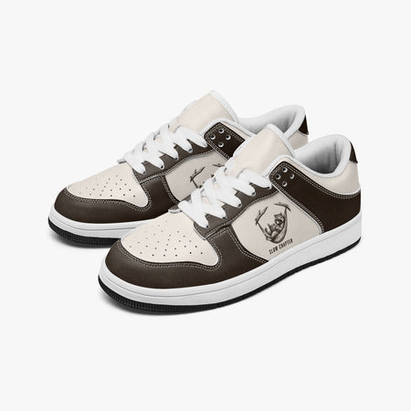 Angled three-quarter view of low-top sneakers in dark espresso brown and cream leather, featuring a raccoon in a hammock illustration with "SLOW CHAPTER", white laces, and a white inner lining.