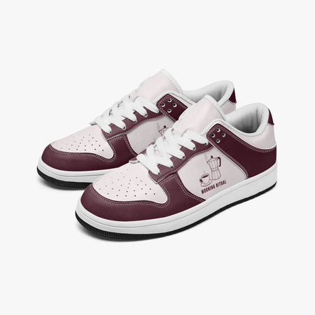 Angled three-quarter view of low-top sneakers in burgundy and pale pink leather, featuring a moka pot and coffee cup graphic with "MORNING RITUAL", white laces, and a white inner lining.