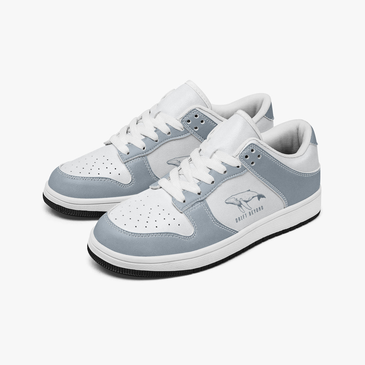 Angled three-quarter view of low-top sneakers in slate blue-grey and white leather, featuring a swimming whale illustration with "DRIFT BEYOND", white laces, and a white inner lining.