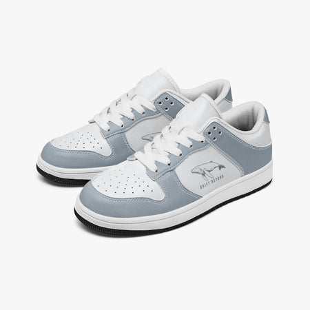 Angled three-quarter view of low-top sneakers in slate blue-grey and white leather, featuring a swimming whale illustration with "DRIFT BEYOND", white laces, and a white inner lining.