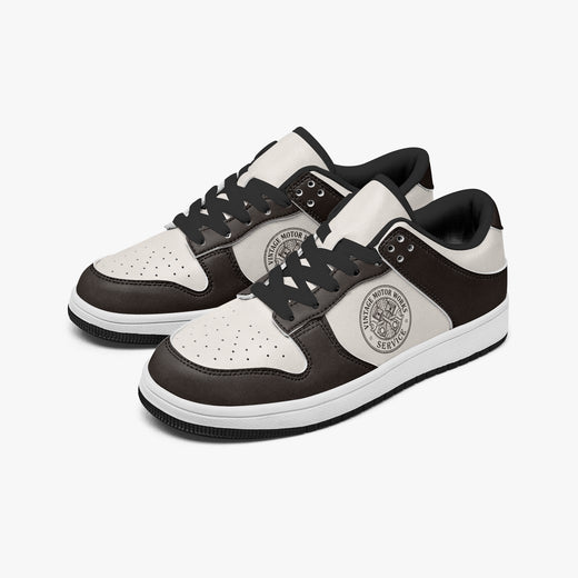 Angled three-quarter view of low-top sneakers in espresso dark brown and off-white leather, featuring a vintage piston graphic with "VINTAGE MOTOR WORKS SERVICE", black laces, and a black inner lining.