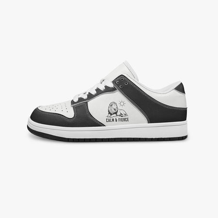 Side profile view of the left sneaker in black and white leather, highlighting the "CALM & FIERCE" lion illustration, white laces, white interior lining, and flat rubber sole facing right.