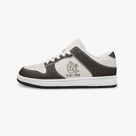 Side profile view of the left sneaker in brown and cream leather, highlighting the "STAY TRUE" nautical compass design, white laces, white interior lining, and flat rubber sole facing right.