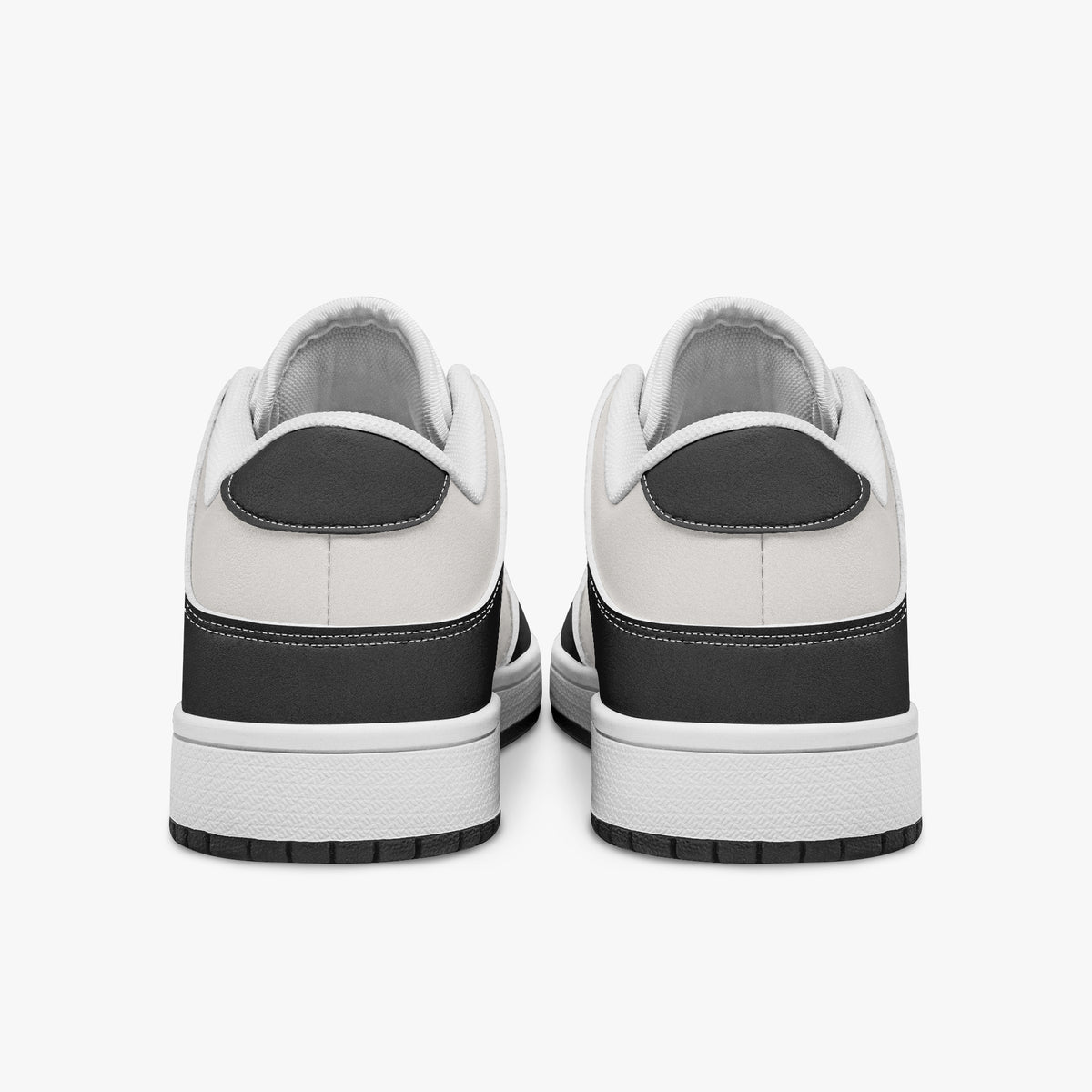 Rear view of black and white sneakers displaying dark charcoal heel overlays, white leather collar panels, and two-tone white and black rubber outsoles.