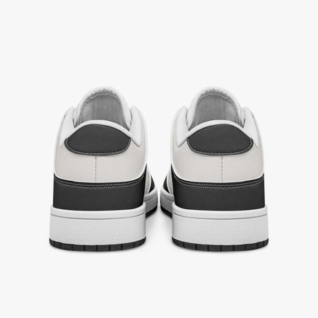Rear view of black and white sneakers displaying dark charcoal heel overlays, white leather collar panels, and two-tone white and black rubber outsoles.