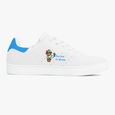 A white low-top sneaker with a bright blue heel tab, featuring a small colorful graphic of a potted cactus with the text 'Too hot to bloom.' on the side, set against a light gray background.