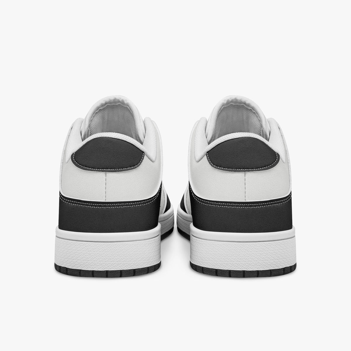 Rear view of black and white sneakers displaying dark charcoal heel overlays, white leather collar panels, and two-tone white and black rubber outsoles.