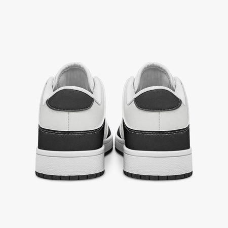 Rear view of black and white sneakers displaying dark charcoal heel overlays, white leather collar panels, and two-tone white and black rubber outsoles.