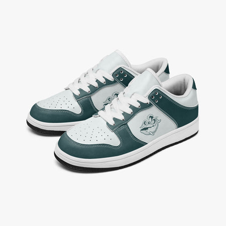 Angled three-quarter view of low-top sneakers in dark teal green and white leather, featuring a whale with ocean waves graphic on the side panel, white laces, and a white inner lining.