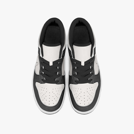 Overhead view of black and white sneakers displaying black laces, black padded collar lining, and perforated white leather toe boxes.