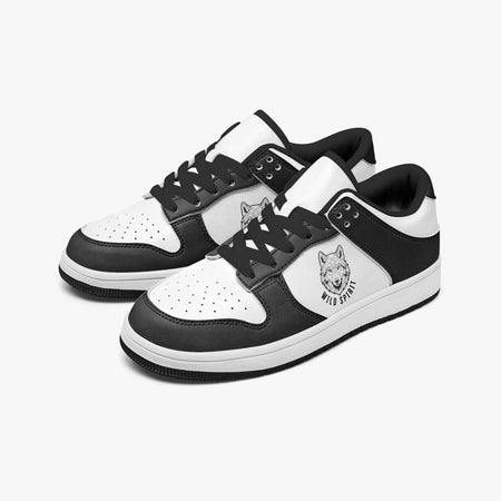 Angled three-quarter view of low-top sneakers in charcoal black and white leather, featuring a wolf head graphic with "WILD SPIRIT", black laces, and a black inner lining.