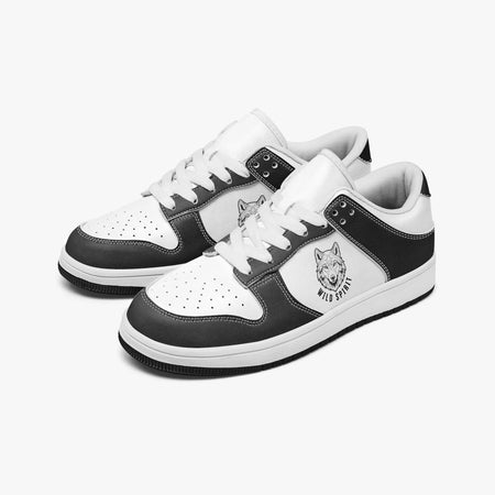 Angled three-quarter view of low-top sneakers in charcoal black and white leather, featuring a wolf head illustration with "WILD SPIRIT", white laces, and a white inner lining.