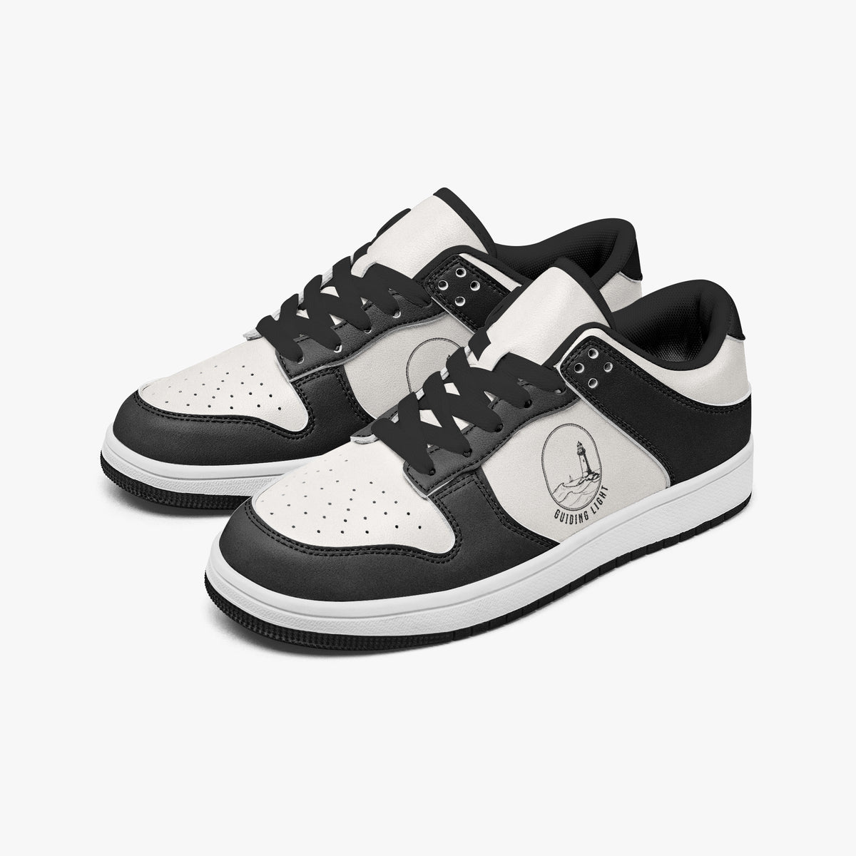 Angled three-quarter view of low-top sneakers in charcoal black and white leather, featuring a lighthouse illustration with "GUIDING LIGHT", black laces, and a black inner lining.