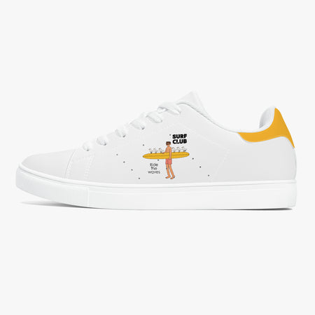 A white low-top sneaker with a yellow heel tab and a cartoon graphic of a surfer carrying drinks on the side. The graphic includes the text 'SURF CLUB' and 'BIG BOY MOVIES'.