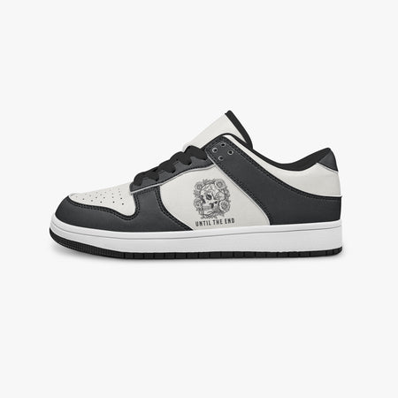 Side profile view of the left sneaker highlighting the black leather panels, floral skull emblem, black interior lining, and flat rubber sole facing right.