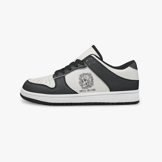 Side profile view of the left sneaker highlighting the black leather panels, floral skull emblem, black interior lining, and flat rubber sole facing right.