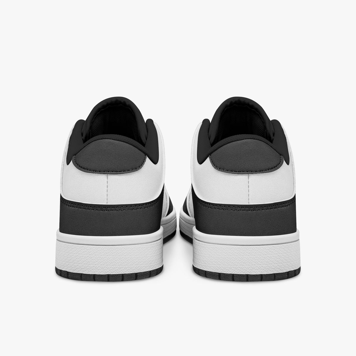 Rear view of black and white sneakers showing dark charcoal heel overlays, white leather collars, and black interior collar lining above white midsoles.