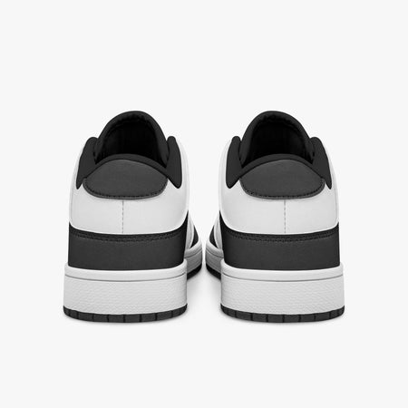 Rear view of black and white sneakers showing dark charcoal heel overlays, white leather collars, and black interior collar lining above white midsoles.