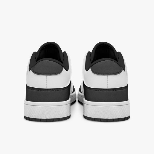 Rear view of black and white sneakers showing dark charcoal heel overlays, white leather collars, and black interior collar lining above white midsoles.