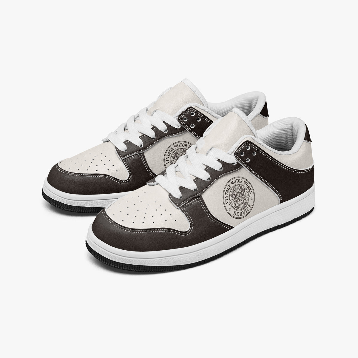 Angled three-quarter view of low-top sneakers in espresso dark brown and off-white leather, featuring a vintage piston emblem with "VINTAGE MOTOR WORKS SERVICE", white laces, and a white inner lining.