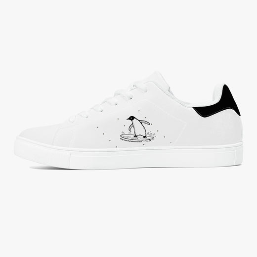 A white low-top sneaker with a black heel tab, featuring a black line-art illustration of a penguin standing on a surfboard on the side, set against a plain white background.