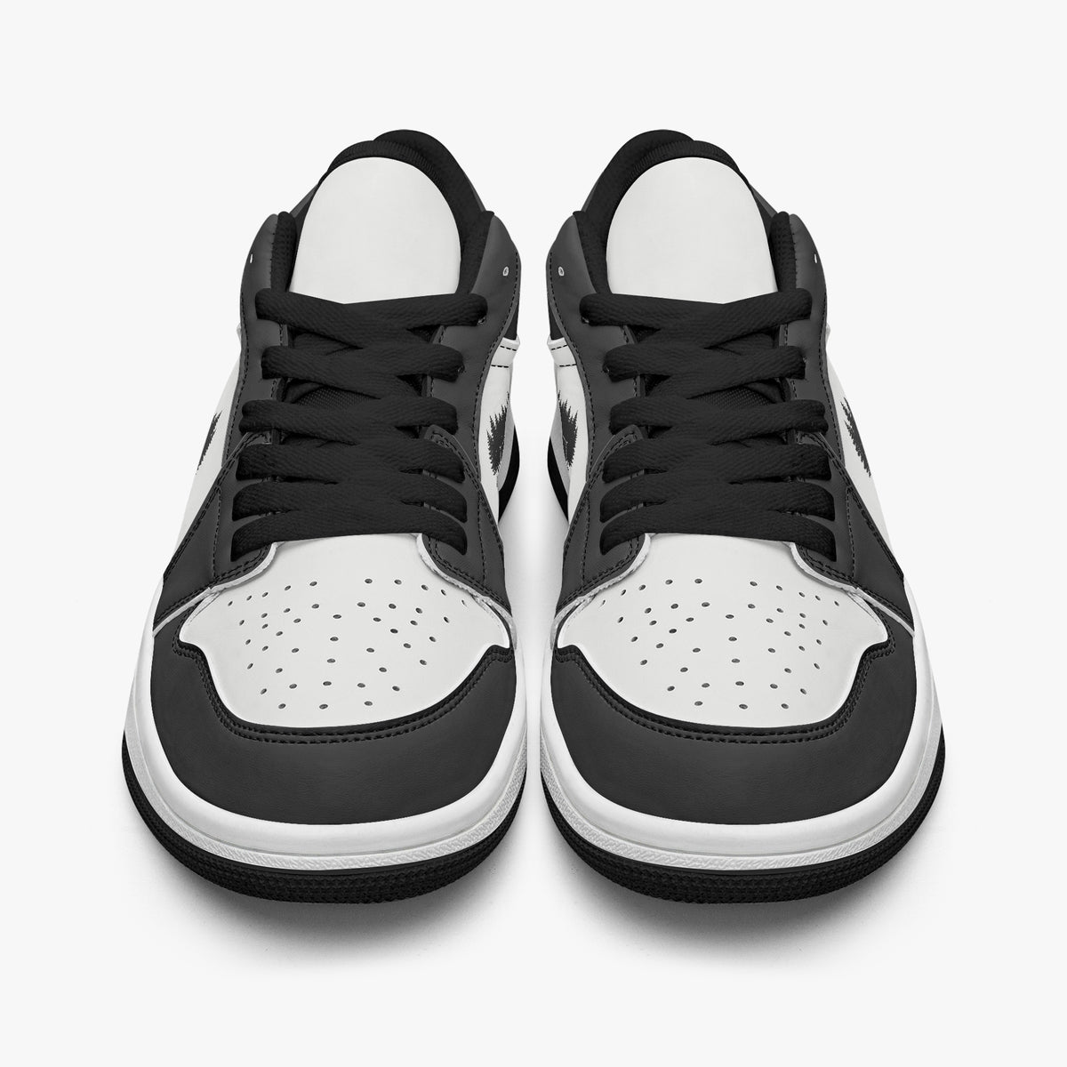 Front-facing eye-level view of black and white low-top sneakers showcasing black laces, black tongue trim, and perforated white toe boxes.