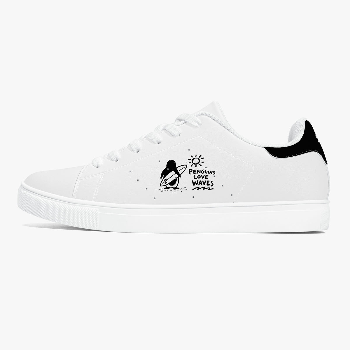 A white low-top sneaker with a black heel tab, white laces, and a black graphic on the side depicting a penguin on a surfboard with the text 'Penguin Surf Waves'.