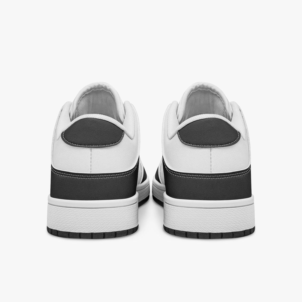 Rear view of black and white sneakers displaying dark charcoal heel overlays, white leather collar panels, and two-tone white and black rubber outsoles.