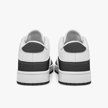 Rear view of black and white sneakers displaying dark charcoal heel overlays, white leather collar panels, and two-tone white and black rubber outsoles.