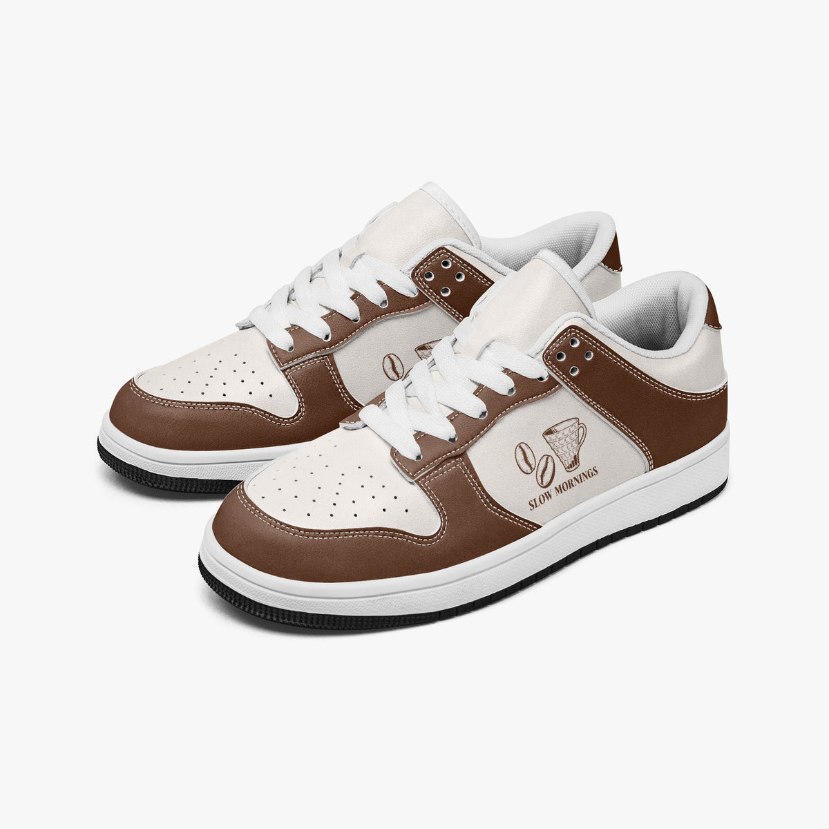 Angled three-quarter view of low-top sneakers in coffee brown and off-white leather, featuring coffee beans and a pour-over dripper cup with "SLOW MORNINGS", white laces, and a white inner lining.