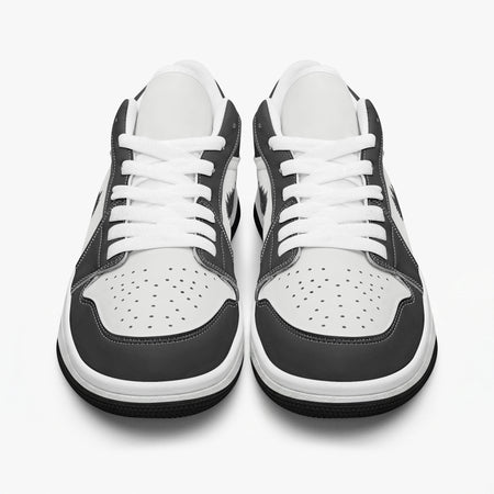 Front-facing eye-level view of black and white low-top sneakers displaying white laces, black eyestays, and perforated white toe boxes.