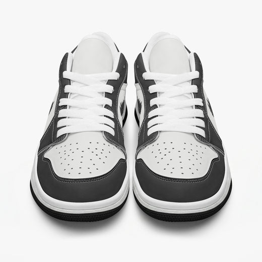 Front-facing eye-level view of black and white low-top sneakers displaying white laces, black eyestays, and perforated white toe boxes.